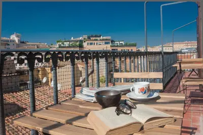 a table with an open book on a balcony with a cup and glasses at Monti Deluxe - Terrace Spectacular View in Rome