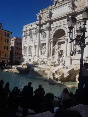 a group of people standing around the trevi fountain at barberini holiday house in Rome