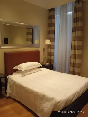 a bedroom with a large white bed with a mirror at Hotel Albergo Santa Chiara in Rome
