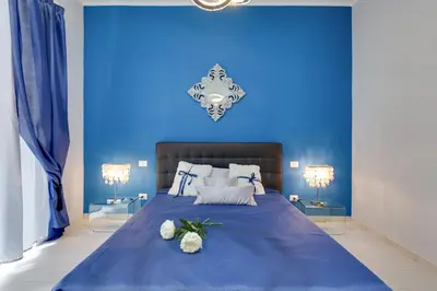 a blue bedroom with a large bed with two lamps at Louise at Colosseum in Rome