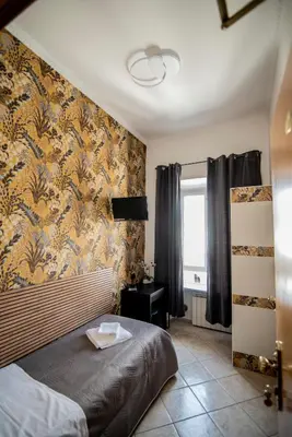 a bedroom with a bed and a wall with wallpaper at Hotel Dell'Urbe in Rome