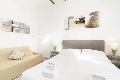 a white bedroom with a bed and a couch at White terrace apartment navona in Rome