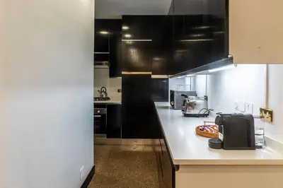 a kitchen with black cabinets and a white counter top at Piazza di Spagna 90 Exclusive Apartment in Rome