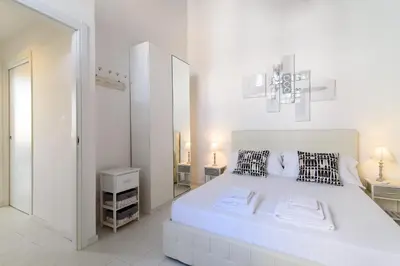 a white bedroom with a large white bed and a mirror at White Terrace Ostilia in Rome
