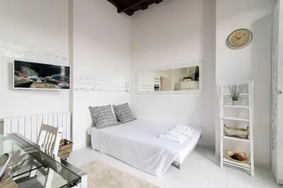 a white bedroom with a bed and a clock on the wall at White Terrace Ostilia in Rome