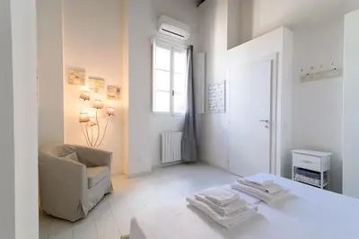 a white living room with a chair and a table at White Terrace Ostilia in Rome