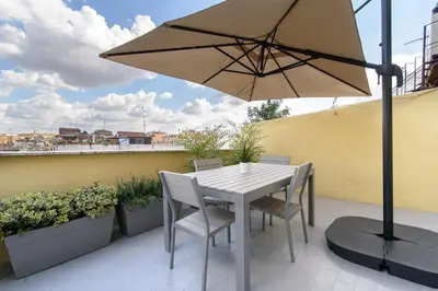a table and chairs with an umbrella on a balcony at White Terrace Ostilia in Rome
