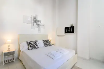 a white bedroom with a bed and a night stand at White Terrace Ostilia in Rome