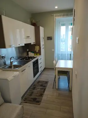 a kitchen with white cabinets and a sink and a table at Sweet home Appio Latino in Rome