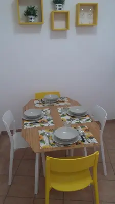 a dining room table with yellow chairs and a tablecloth at Casa Giramondo in Rome
