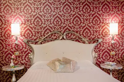 a bedroom with a white bed with red wallpaper at Locanda Del Sole-Roma Piazza Di Spagna Ripetta in Rome