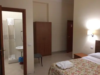 a bedroom with a bed and a bathroom with a sink at Albergo Enrica in Rome