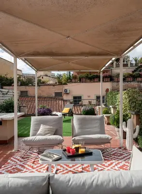a patio with two couches and an umbrella at Trevi Luxury Terrace in Rome