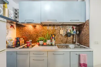 a kitchen with white cabinets and a brick wall at Diana Romantic Loft in Rome