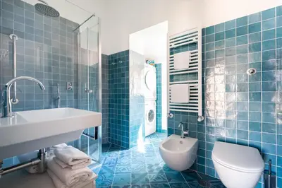 a blue tiled bathroom with a sink and a toilet at Trevi Comfortable Apartment with Terrace | Romeloft in Rome