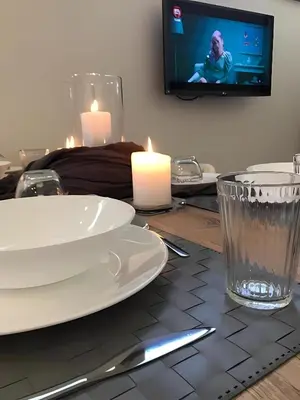 a table with white plates and candles and a tv at MVM Apartment in Rome