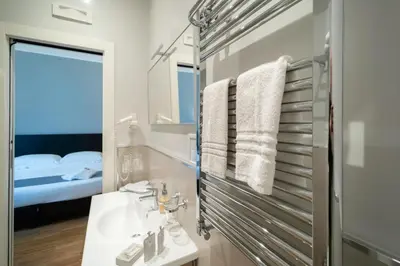 a bathroom with a sink and a mirror and a bed at At Home Townhouse - Filiberto in Rome