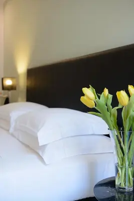 a vase with yellow flowers on a table next to a bed at At Home Townhouse - Filiberto in Rome