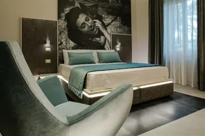 a bedroom with a bed and a chair in it at Via Veneto Luxury Suites in Rome