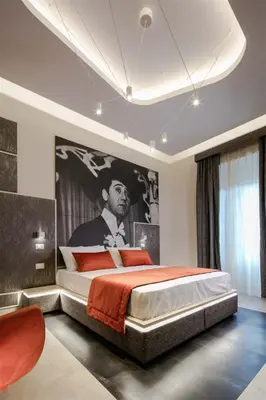 a bedroom with a large bed with a painting on the wall at Via Veneto Luxury Suites in Rome