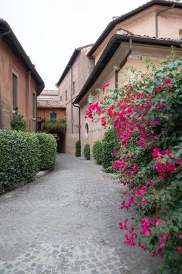 a cobblestone street with pink flowers in front of a building at Forum Apartment in Rome