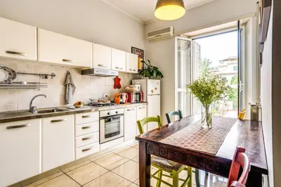 a kitchen with white cabinets and a wooden table at Circus Maximus Home in Rome