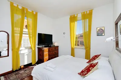 a bedroom with a bed and a tv and two windows at Trastevere Lovely Studio Apartment in Rome