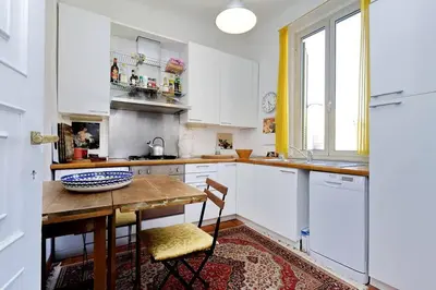 a kitchen with white cabinets and a wooden table at Trastevere Lovely Studio Apartment in Rome