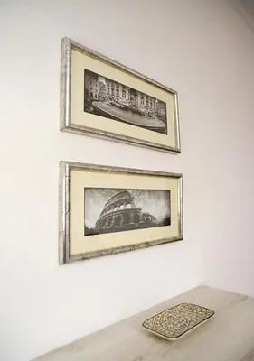 two framed pictures on a white wall with a table at Colosseum Comfortable Apartment in Rome