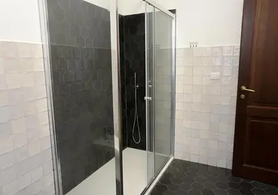 a bathroom with a glass shower with black and white tiles at Colosseum Comfortable Apartment in Rome