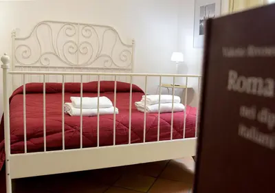a bedroom with a bed with red sheets and white pillows at Colosseum Comfortable Apartment in Rome