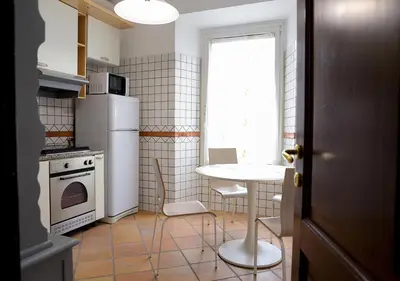 a kitchen with a table and a white refrigerator at Colosseum Comfortable Apartment in Rome
