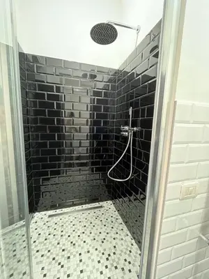 a bathroom with a shower with a black brick wall at 2 Passi Da in Rome