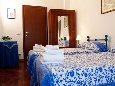 a bedroom with two beds with blue and white sheets at 2 Passi Da in Rome