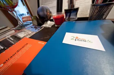 a blue and orange book on a table with a drink at 2 Passi Da in Rome
