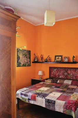 a bedroom with orange walls and a bed with a quilt at 4321 B&B Stazione Trastevere in Rome