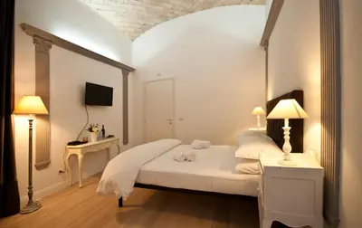 a bedroom with a white bed with two lamps at B&B La finestra sul Colosseo in Rome