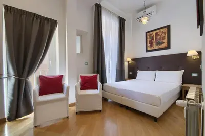 a bedroom with a white bed and two chairs at Gli Artisti Apartments Rome in Rome