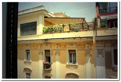 a yellow building with a balcony with flowers on it at Hotel Louisiana in Rome
