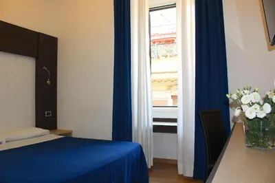 a bedroom with a bed and a window with a vase of flowers at Hotel Louisiana in Rome