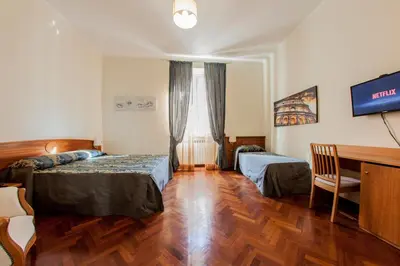 a room with two beds and a desk and a television at Hotel Domus Praetoria in Rome