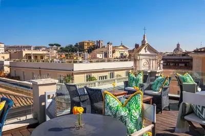 a patio with tables and chairs on a roof at Singer Palace Hotel Roma in Rome