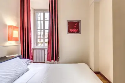 a bedroom with a bed and a window with red curtains at Guest House Trastevere in Rome