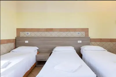 two beds in a room with white sheets at Alex Romano in Rome