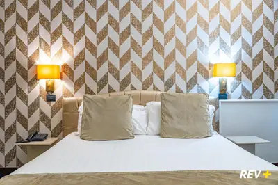 a bed with two pillows in a bedroom with two lamps at Via Veneto Suites in Rome
