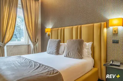 a bedroom with a large bed with a yellow headboard at Via Veneto Suites in Rome