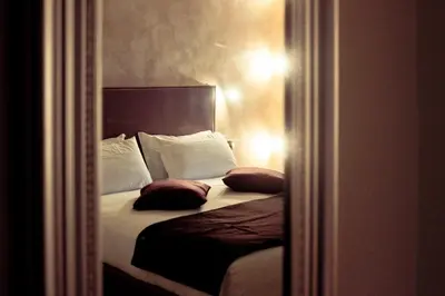 a bedroom with a bed with white pillows and a mirror at Rome By Suite Vatican in Rome