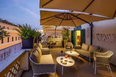 a patio with tables and chairs and an umbrella at Hotel Regno in Rome