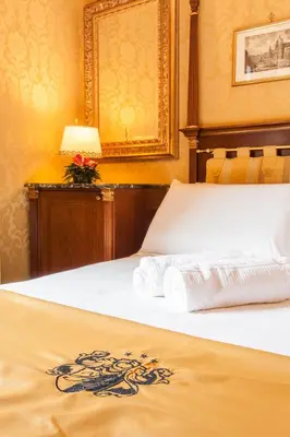 a bedroom with a bed with a white bedspread and a lamp at Hotel Manfredi Suite In Rome in Rome