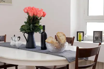 a white table with a vase of flowers and bread at Monti Central Apartment in Rome